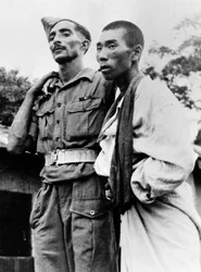 Ein Sanitäter der indischen Armee hilft einem verwundeten japanischen Kriegsgefangenen, 1945